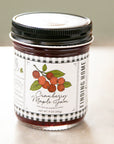 Jar of cranberry maple jam with a checkered label on a light background