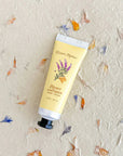 Hand cream tube labeled 'Honey Lavender' on a textured background with floral decorations