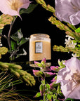 Jar of Voluptuous Vanilla in a circular arrangement of flowers on a black background