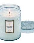 light blue glass jar candle with lid off. Flame is burning