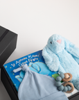 Baby gift set with blue plush bunny, book, and rattle on a white background