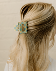 Blonde hair with a decorative hair clip against a beige background