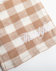 Checkered napkin with 'Thankful' embroidery on a white background