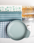 Collection of kitchen items including a jar, lid, and towels on a white background