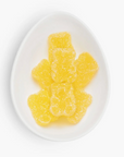 Yellow gummy bear on a white plate with a white background