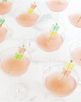 Cocktail glasses with pink liquid and butterfly cocktail picks on a white background