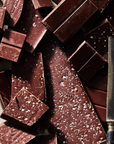 Dark chocolate bars with a knife on a white surface