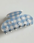 Decorative wall hook with blue and white checkered pattern and floral designs on a light gray background