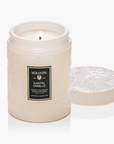 White candle in a textured container with 'Voluspa' label on a white background