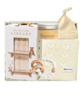 A baby gift set featuring a wooden toy library bookshelf, a cream-colored 'Ihamour' jar candle, a knitted cream baby blanket with heart patterns, and a wooden teething ring with white beads, all arranged in a white gift box.