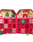 A red Christmas advent calendar opened wide to reveal 24 numbered gift boxes with festive illustrations, including Santa, a Christmas tree, reindeer, and ornaments. Small candy and gift pieces are scattered around the base on a clean white background.