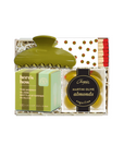 A gift set containing a green hair claw clip, a box of Here's How soap, and a bag of Chogokin Martini olives and almonds, arranged in a clear gift box with shredded paper and gold polka dots.