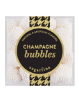 A clear square plastic container filled with white champagne bubbles gum, featuring a large black and gold circular label that reads 'CHAMPAGNE bubbles' and 'sugarfina'.
