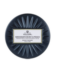 A round dark navy blue tin of Voluspa Maxissim Esbery & Peach Extrait Parfum, shown from a top-down view on a solid white background.
