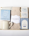 Gift set with mug, tea, socks, and shower steamers on a white background