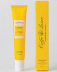 Yellow lip balm tube and packaging on a light gray background