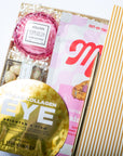 Collagen eye mask, Voluspa product, and a magazine on a white surface with a gold and white striped background.