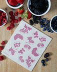 Dishcloth with berry pattern on a wooden surface with bowls of berries