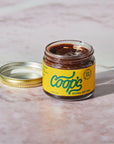 Jar of Coop's Original Hot Fudge on a marble surface