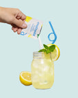 pouring packet into mason jar filled with lemonade and garnished with a lemon