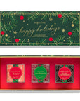 Sugarfina Happy Holidays Candy Bar Gift Set, featuring a dark green illustrated box lid with gold and red holiday details, and an open red box containing three individually wrapped candy bars: Champagne Bears, Sugared Cranberries, and Dark Chocolate Sea Salt Caramels.