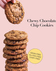 Stack of chewy chocolate chip cookies with a hand holding one above, on a pink background.