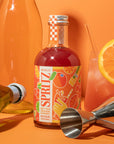 Spritz mixer bottle with cocktail ingredients on an orange background