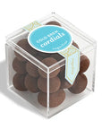 Clear cube box with brown round candies and a blue label on a white background
