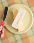 Butter block with a knife on a yellow plate on a checkered tablecloth