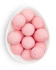 Pink round candies in a white bowl on a white background