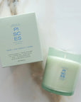 Green candle and packaging labeled 'Pisces' on a marble surface