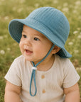 baby wearing a blue bucket hat on a field