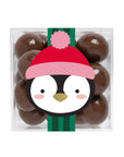 A clear square plastic container filled with glossy dark brown chocolate-covered candies, decorated with a penguin illustration wearing a red and pink Santa hat and green striped scarf on a white background.