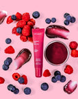 purple lip gloss surrounded by blueberries & raspberries