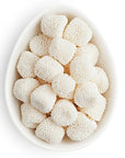 White spherical candies in a white bowl on a white background