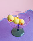 Candle in a glass holder with three yellow candles on a purple surface