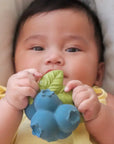 Baby holding a blueberry-shaped teething toy with green leaves