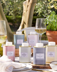 Table setting with striped candles and glasses of white wine outdoors.