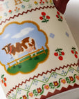 Close-up of a ceramic mug or cup with a cream-colored glaze, decorated with a colorful pastoral scene featuring a brown and white cow in a field, surrounded by floral and zigzag patterns.