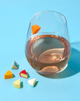 Glass of rose wine with colorful candy pieces on a blue background