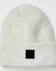 White textured beanie with a black square patch on a white background
