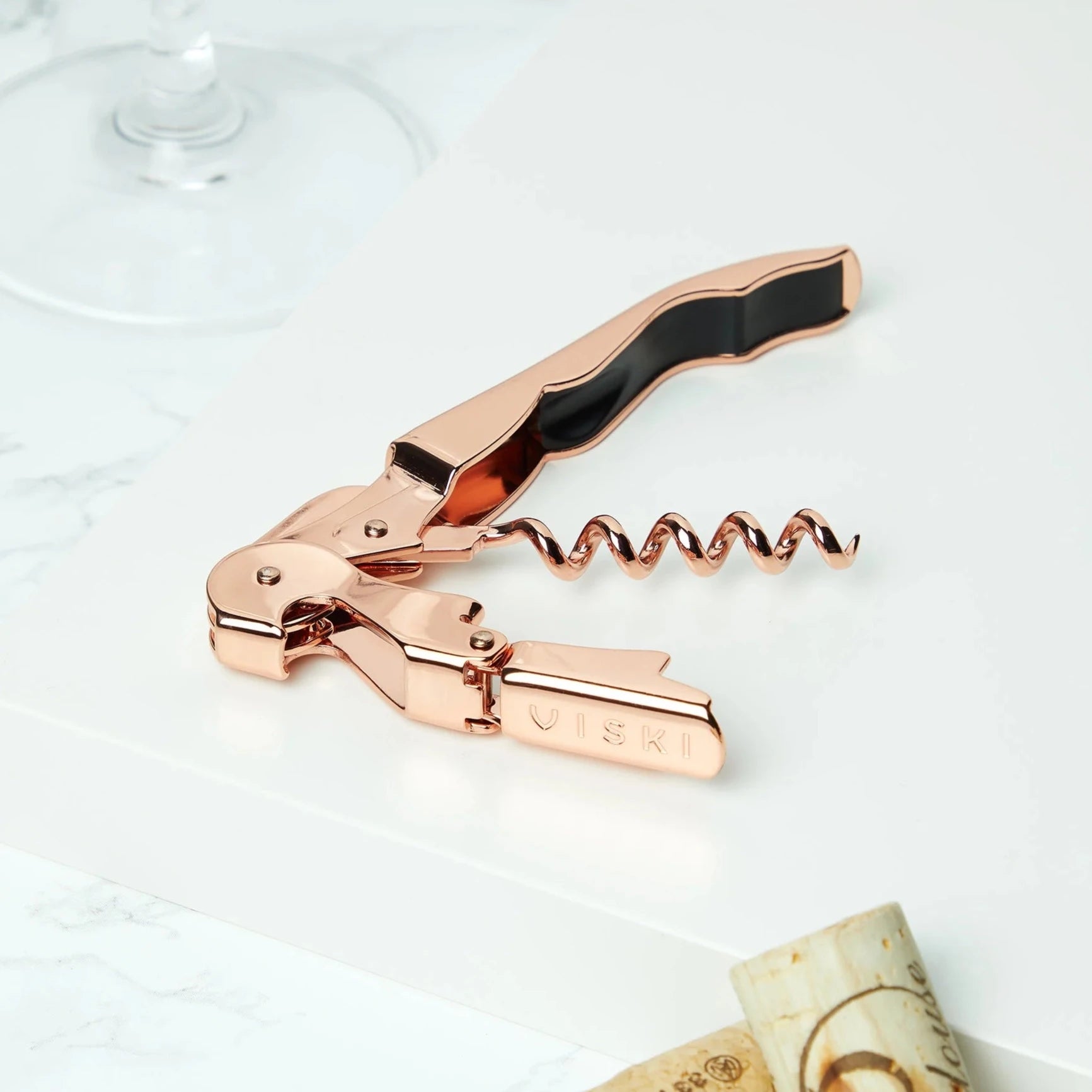 Copper Corkscrew on tray next to glass and corks