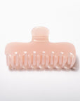 A translucent pale pink hair claw clip on a clean white background.