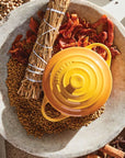 Yellow kitchen tool on a stone surface with dried herbs and spices