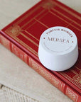 White jar of Mersea pumpkin whip on a red book