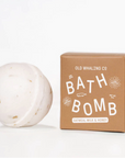 White round bath bomb next to a brown box with white writing.
