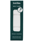 A tall rectangular dark teal box with clear window in middle showing stack of white shower steamers. White text on packaging reads, "Latika Self Care Shower Steamers fresh and warm scent of oats and raw honey"