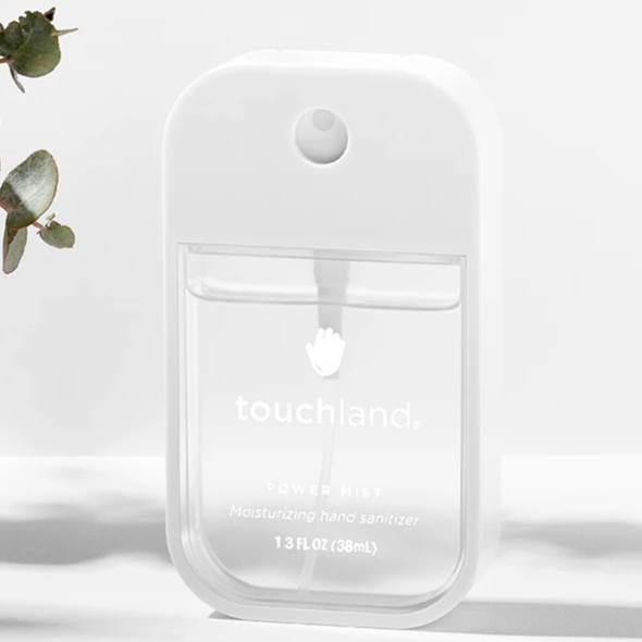 Clear hand sanitizing spray on white background with eucalyptus branch off to the side.