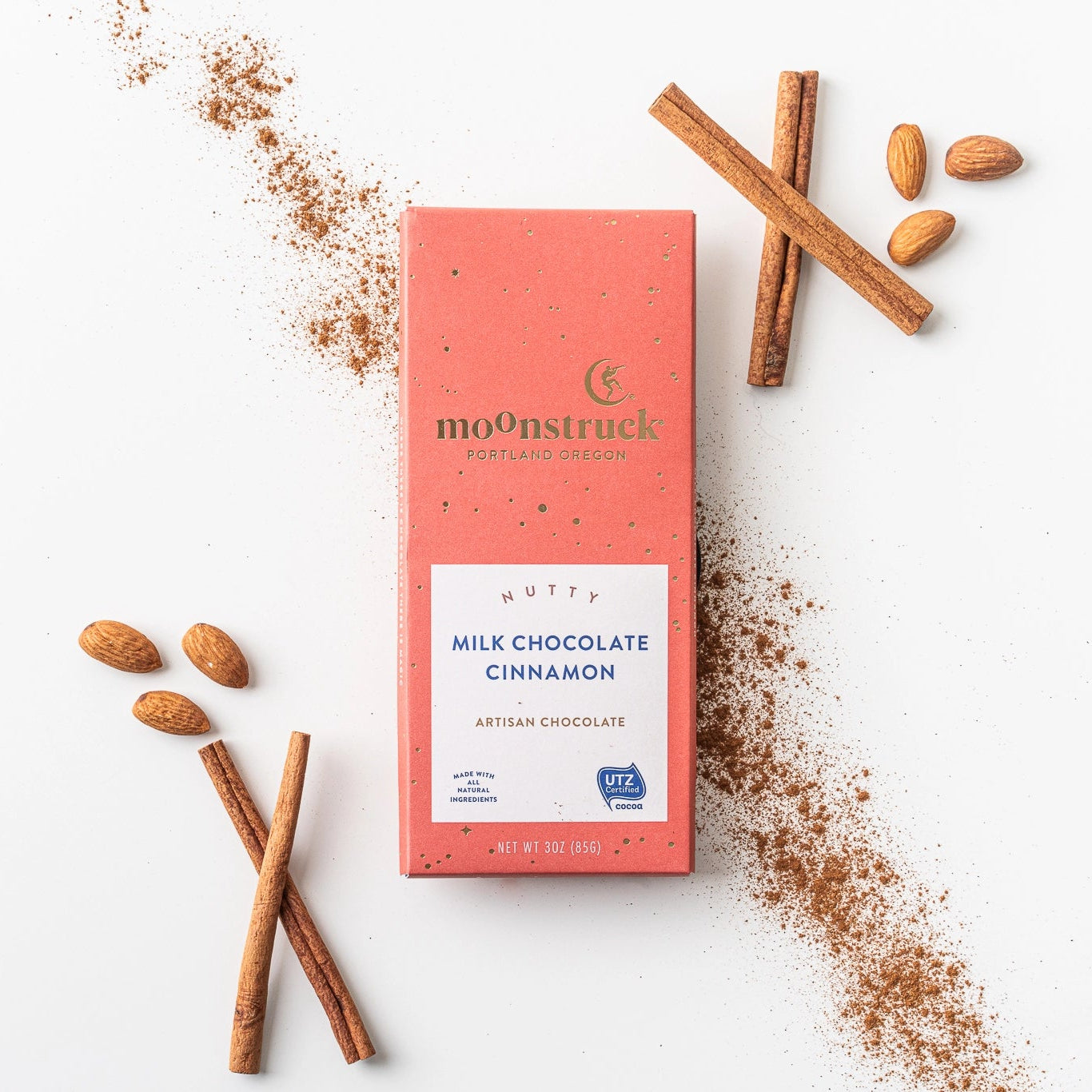 Moonstruck milk chocolate cinnamon bar with cinnamon sticks and ground cinnamon on a white background