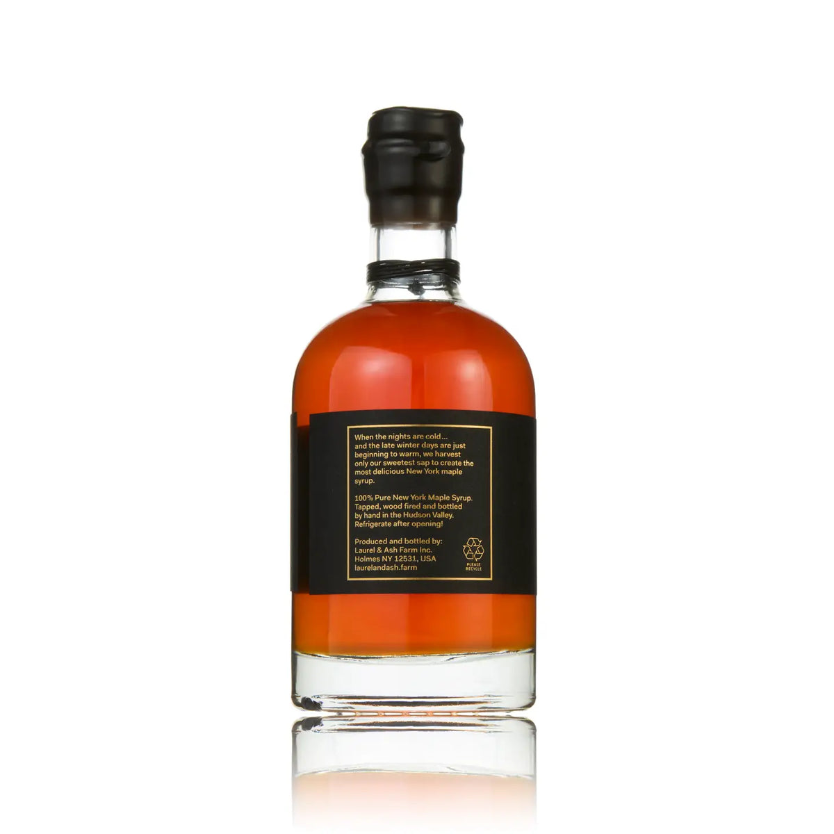 A bottle of Scotch whisky shown from the back, featuring a black label with gold text and a black screw cap, set against a plain white background with a soft reflection.